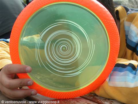Child in striped shirt holding an orange frisbee in front of face