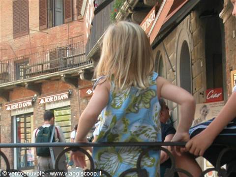 Blonde girl watches Siena's piazza over the wrought iron railing