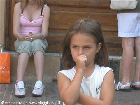 Thoughtful little girl with hand near mouth in front of wooden door