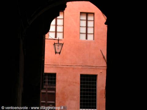Lantern on a pink house wall seen through a dark arch