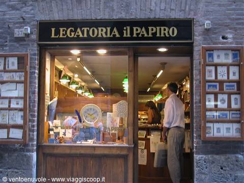 Customer entering the il Papiro bookbinding shop among print displays and green lamps