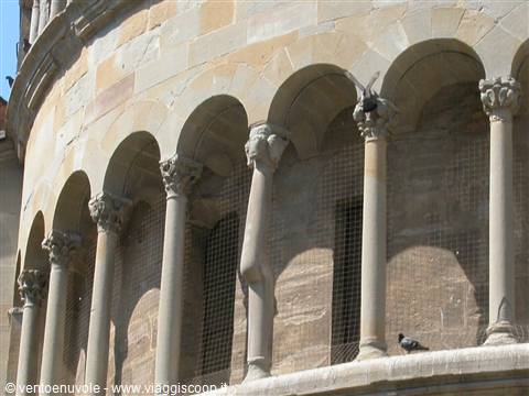 Marble columns and arches of Pisa Tower, pigeon among capitals, sunlight