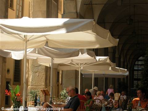 White umbrellas shading café tables beneath Bologna's medieval arcades