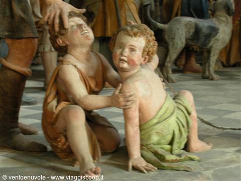 Terracotta statues of crouching children, a dog behind, inside a baroque chapel
