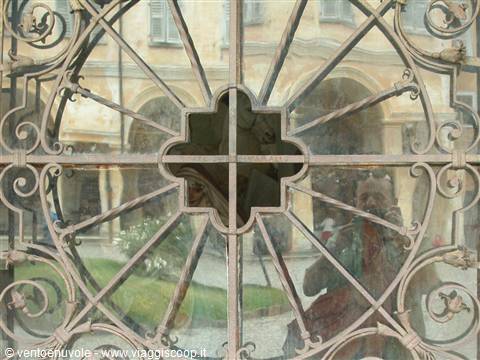 Wrought iron grille with central rosette in front of an arcaded courtyard