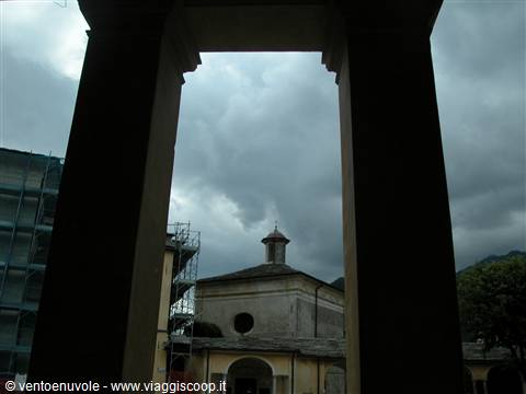 Small church with dome seen through portico columns under cloudy sky