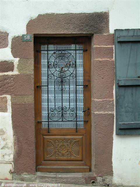 Carved wooden door with wrought iron grille, pink stone wall