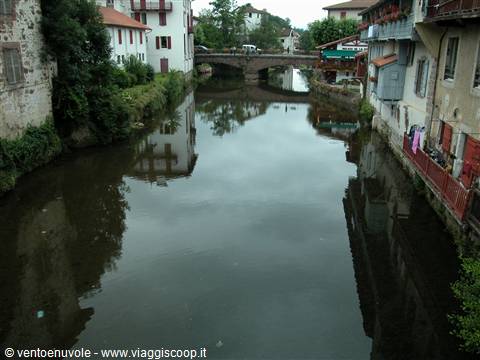 Nive river flowing past half-timbered houses and a stone bridge in Saint-Jean-Pied-de-Port