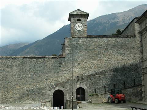 Stone walls of Forte di Bard, clock tower, cloudy mountains, small red tractor