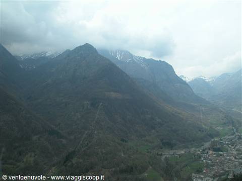 Bare mountains among clouds above a green valley with a village