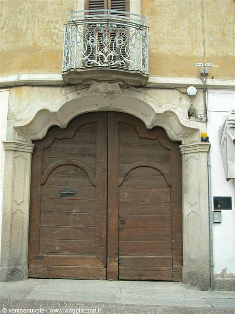 Old wooden doorway with baroque stone frame, wrought iron balcony above