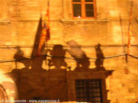 Shadows of flags and statues projected on a stone building facade