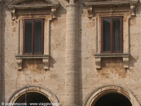 Stone facade with two wooden windows and central column in warm sunlight