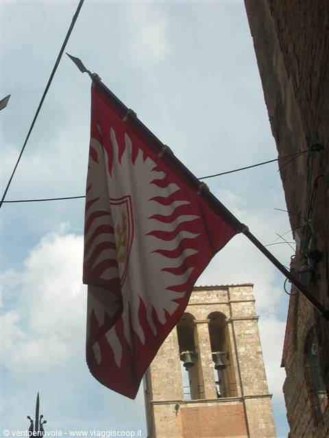 Red banner with golden sun waves over a medieval stone bell tower