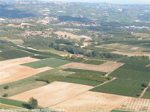 Cultivated fields and hillside vineyards with villages in the distance under daylight