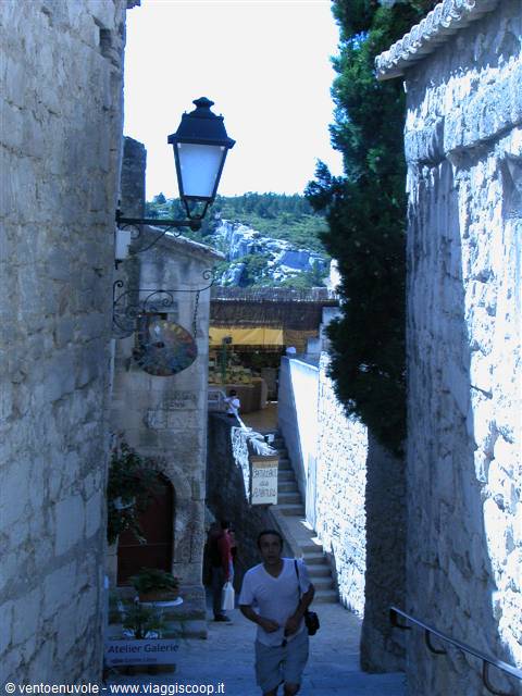 Tourist walking down stone steps between old houses, black lantern and craft shop