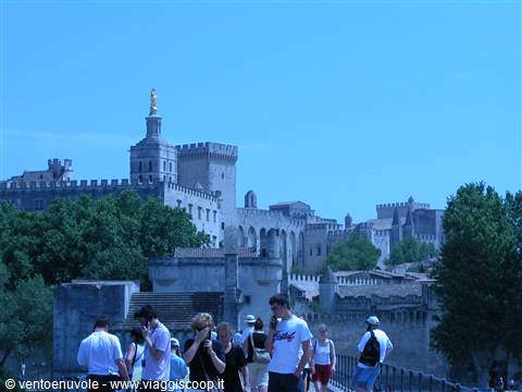 Tourists walk in front of the Popes' Palace in Avignon, stone walls