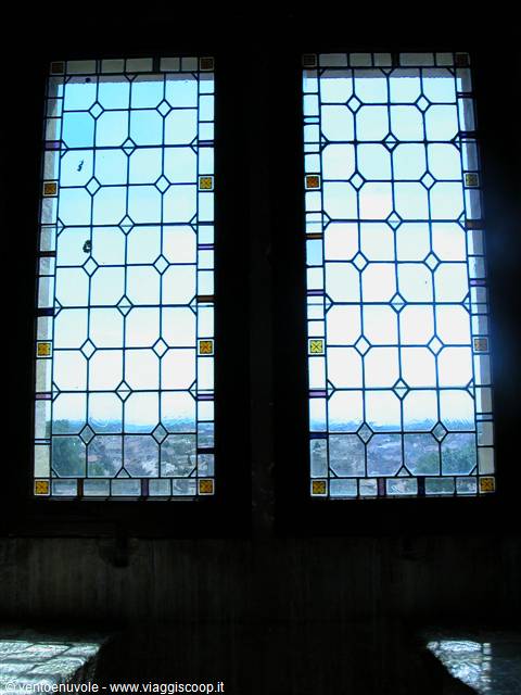 Two leaded stained glass windows lit by sky, distant town visible below