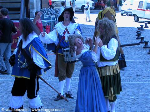 Costumed historical figures dance on a stone-paved square