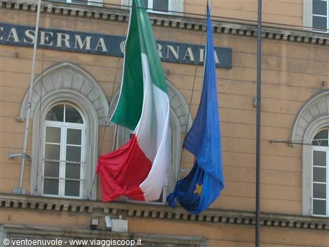 Italian and EU flags waving in front of the Caserma Vernara building