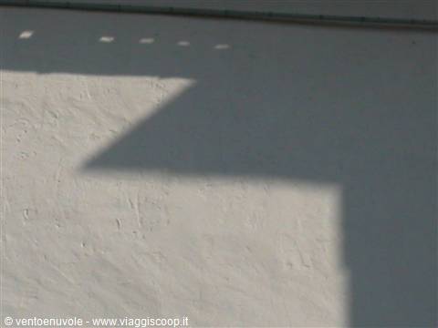 Roof shadow on a white plastered wall in sunlight