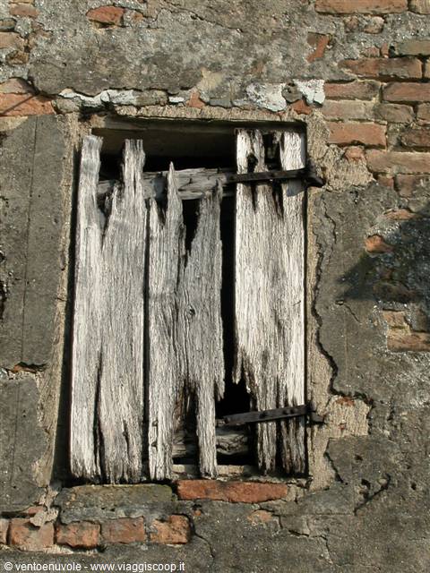 Old window with rotten wooden shutters on brick wall