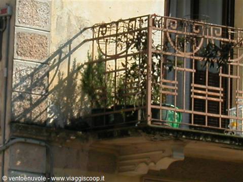 Wrought iron balcony with rosemary pots, morning light on plastered facade