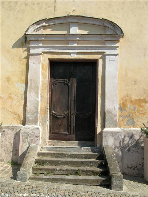 Dark wooden doorway with curved pediment and stone steps on yellow facade