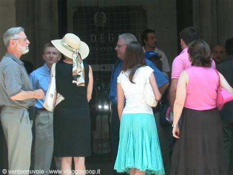 Tourists in summer clothes in front of a marble building entrance