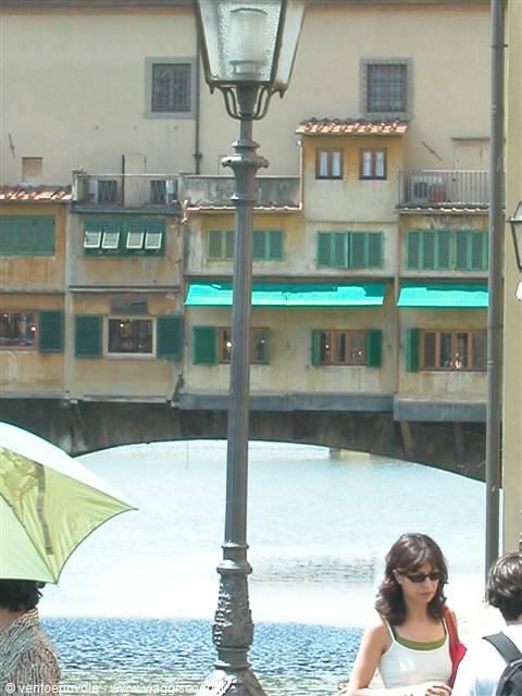 Tourists under a parasol in front of Ponte Vecchio over the Arno, Florence