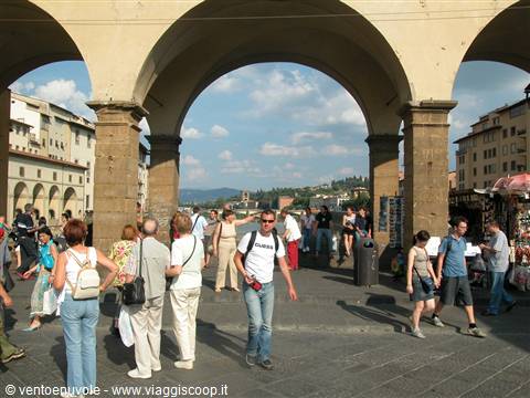 Tourists walking under the stone arches of Ponte Vecchio, Florence