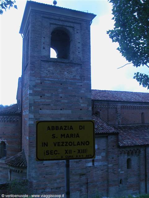 Yellow sign of Abbazia di S. Maria in Vezzolano in front of the brick bell tower