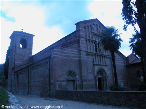 Romanesque brick facade and bell tower of Vezzolano Abbey among palm trees