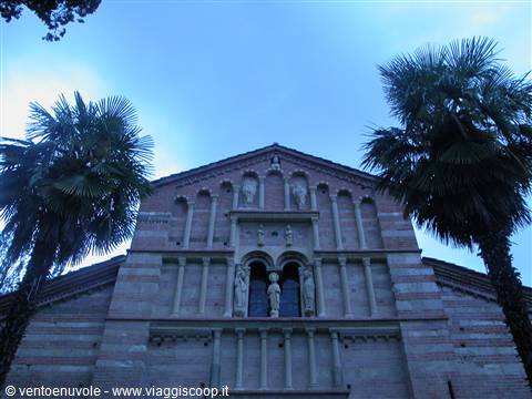 Romanesque brick and stone facade with statues framed by two palms, Pomposa Abbey