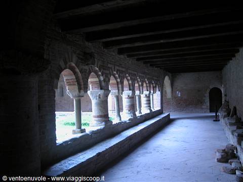 Medieval cloister with brick arches and columns, natural light on the arcade