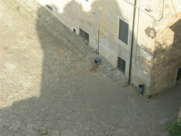 Person sitting on stone steps beside an old sunlit building