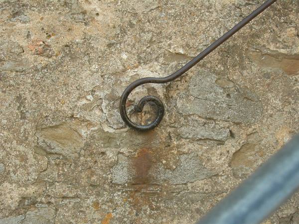 Wrought iron handrail ending in a spiral curl on stone wall