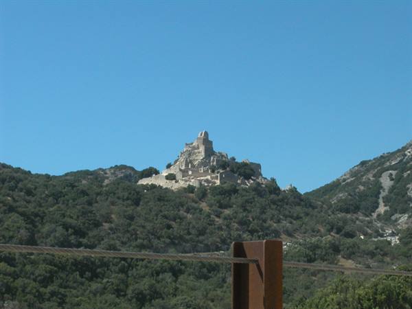 Stone fortress on green hill, clear blue sky, steel cable in foreground