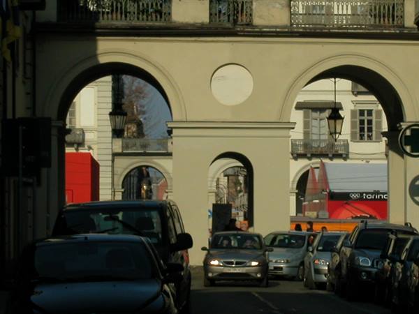 Arched porticoes over a busy street, torino sign visible