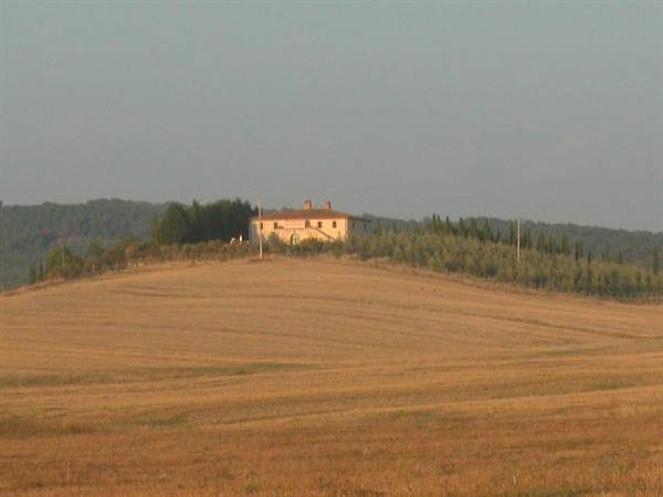 Hilltop farmhouse among golden fields and cypress trees, Tuscan countryside