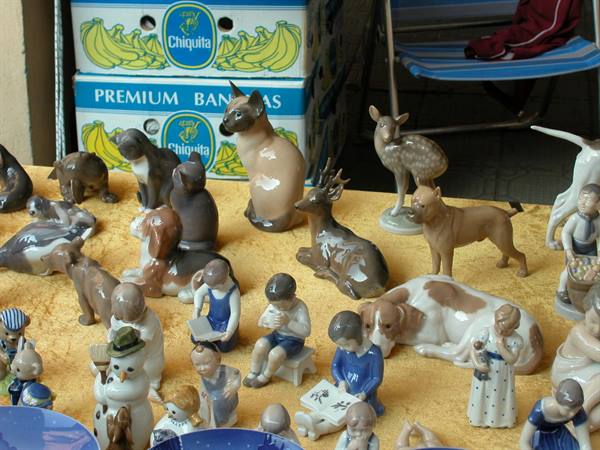 Porcelain figurines of animals and children for sale, behind Chiquita boxes