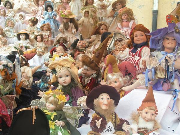Many porcelain dolls and elves displayed on a market stall table