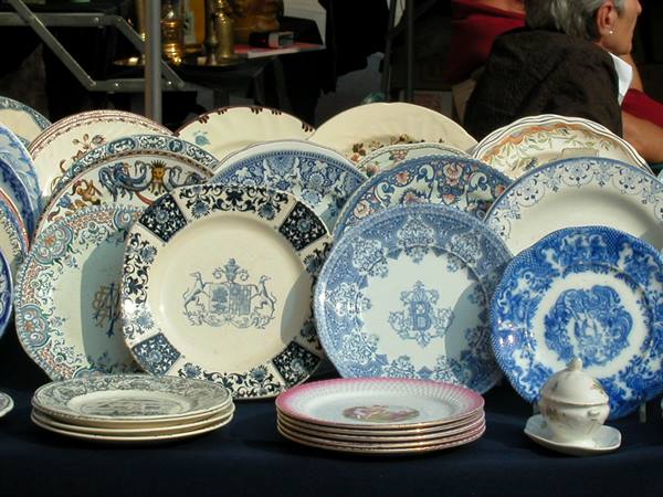 Antique decorated ceramic plates displayed at a flea market, natural daylight