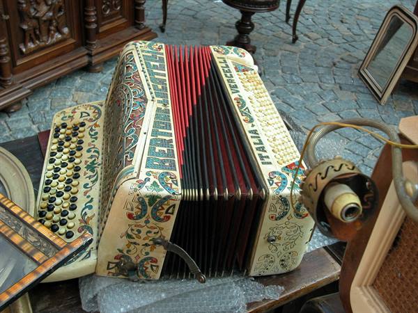 Painted Bertram Dipenden accordion resting on a table among antiques