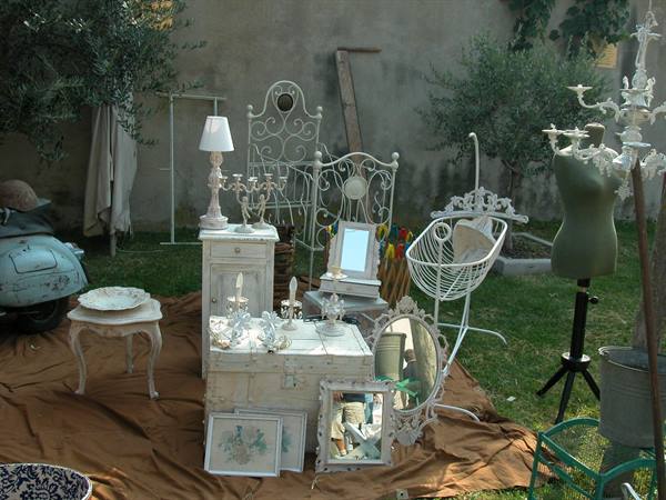 White shabby furniture and objects for sale on brown cloths in a garden