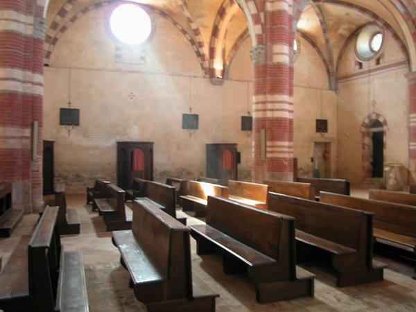Wooden pews beneath brick vaults inside Staffarda Abbey