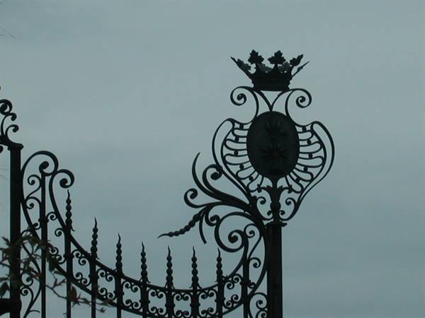 Wrought iron gate with crown and crest, grey sky