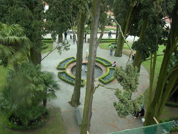 View from above of a garden with circular fountain, flowerbeds and visitors