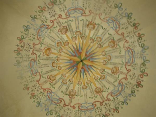 Frescoed sail vault with painted wind rose, angels and colored garlands on pale plaster