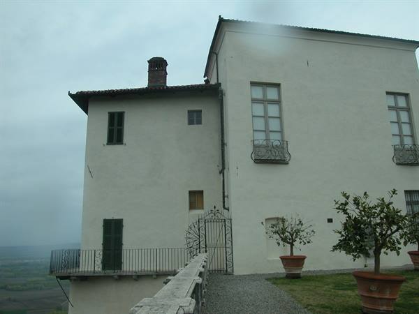 White villa with wrought iron balcony and potted citrus trees, grey sky